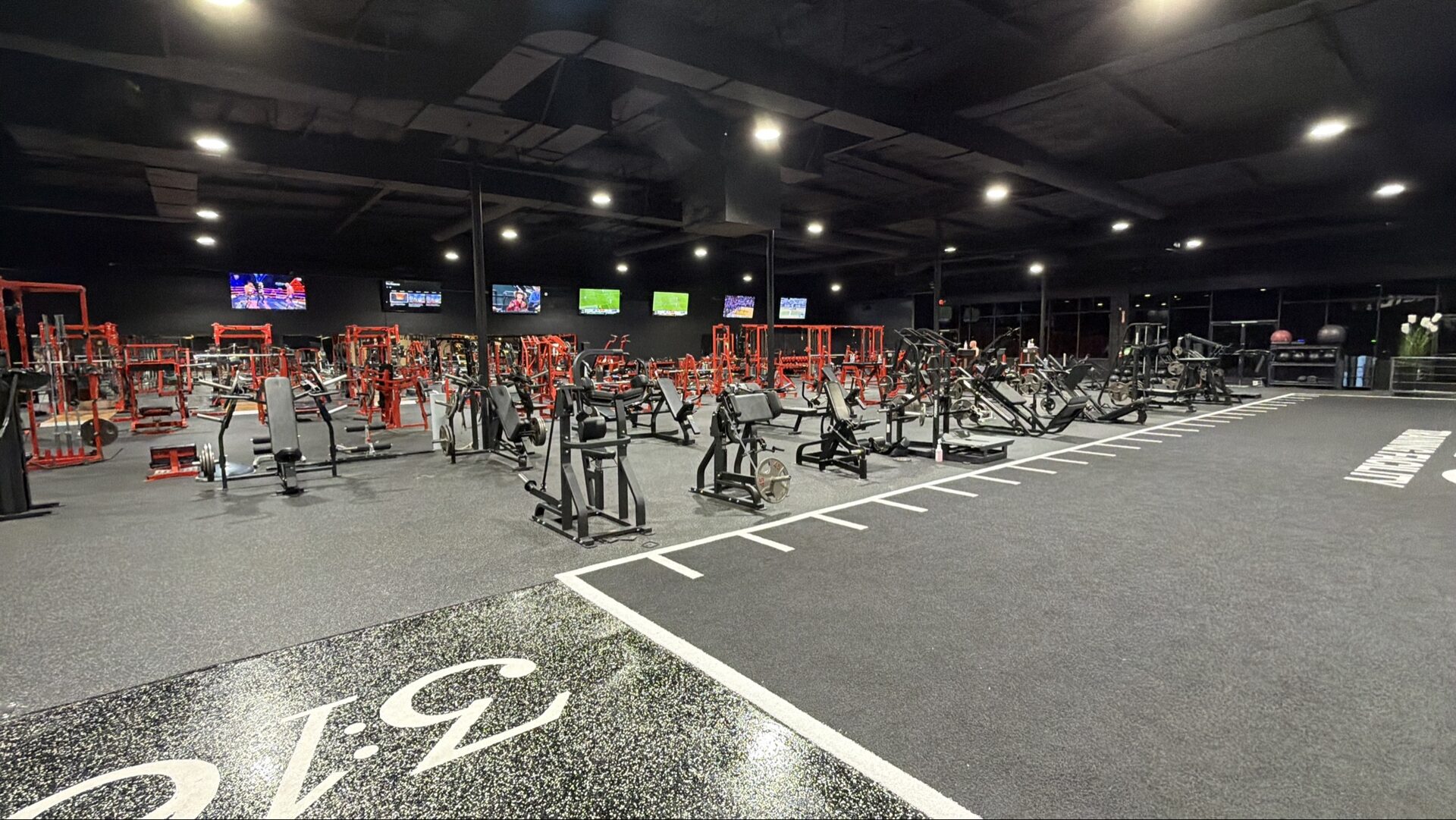 Wide view of the strength floor with red racks and machines